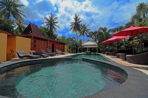 a swimming pool with chairs and umbrellas next to a house at Salim Beach Resort in Gili Air