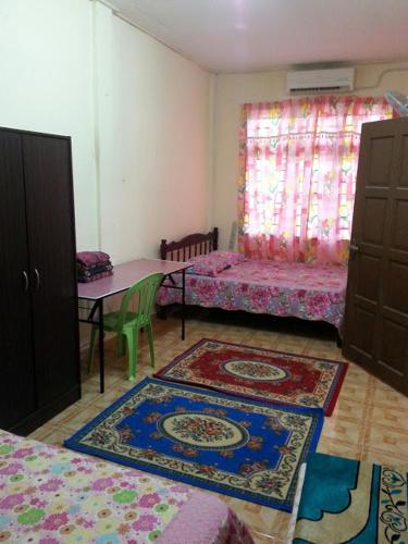 a room with two beds and a table with rugs at Homestay Taman Maktab Pengkalan Chepa in Pengkalan Cepa