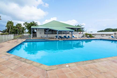 une grande piscine bleue avec un kiosque dans l'établissement STUDIO, PISCINE ET VUE MER A LA MARINA, au Gosier