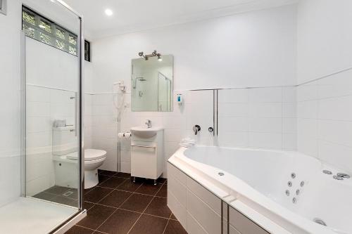 a bathroom with a tub and a toilet and a sink at Commodore Regent in Launceston