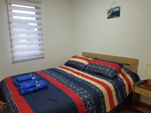 ein Schlafzimmer mit einem Bett mit einer bunten Decke und Kissen in der Unterkunft Turismo FORTALEZA PATAGONIA in Puerto Natales
