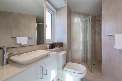 a bathroom with a toilet and a sink and a shower at Cottesloe Blue Apartment in Perth