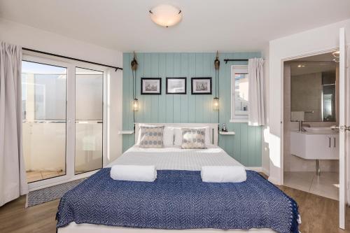 a bedroom with a large bed and a bathroom at Cottesloe Blue Apartment in Perth