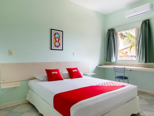 1 dormitorio con 1 cama grande con almohadas rojas en OYO Hotel Cosmópolis, Sao Paulo, en Cosmópolis