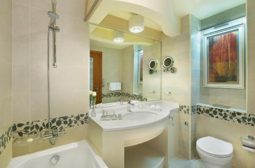 a bathroom with a sink, toilet, mirror and bathtub at City Seasons Towers Hotel Bur Dubai in Dubai