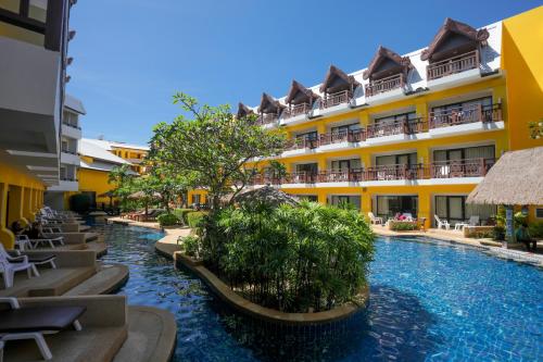 a hotel with a swimming pool in front of a building at Woraburi Phuket Resort & Spa - SHA Plus in Karon Beach