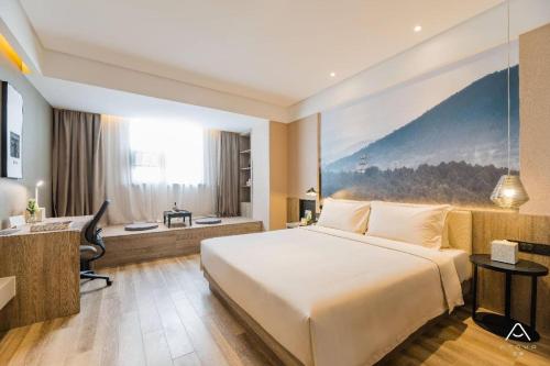 南京市にあるAtour Hotel Maqun Nanjingのベッドとデスクが備わるホテルルームです。