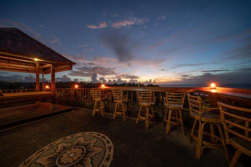 a bar with chairs and a view of the ocean at night at Dreamland View in Uluwatu