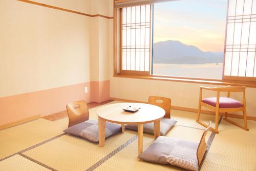 富士河口湖町にある富士河口湖温泉 ホテル あさふじのテーブルと椅子、窓が備わる客室です。