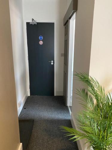 a hallway with a black door and a plant at Bentley House with en-suites in Crewe