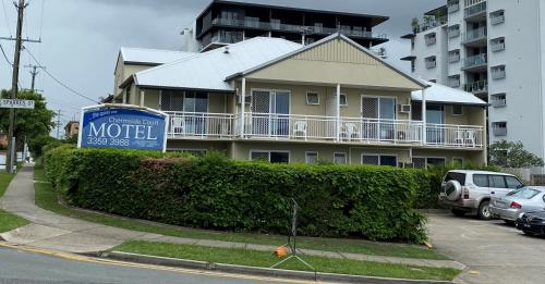 a white house with a blue car parked in front of it at Chermside Court Motel in Brisbane