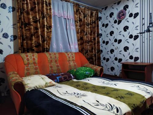 um sofá laranja sentado numa sala com cortinas em посуточная аренда Прокофьева 36 em Sumy