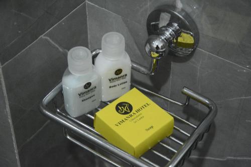 two bottles of soap and a yellow box on a shelf in a bathroom at Vimanra Udawalawa in Udawalawe