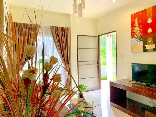 sala de estar con mesa de cristal y TV en Kannapat House, en Ban Nong Thale