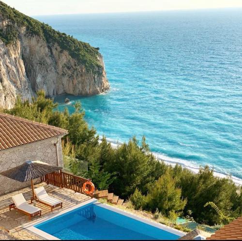 une maison avec une piscine à côté de l'océan dans l'établissement Milos Paradise Luxury Villas, à Agios Nikitas