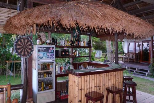 a bar in a straw hut with a refrigerator and stools at Romantic Beach Villas in General Luna