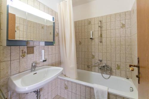a bathroom with a sink and a bath tub at Mountain Hotel & Hostel in Ramsau am Dachstein
