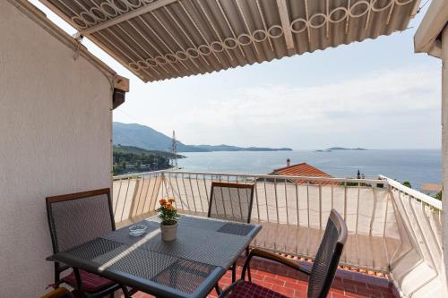 einen Tisch und Stühle auf einem Balkon mit Blick auf das Wasser in der Unterkunft Apartments Kisic in Mlini