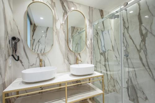 uma casa de banho com dois lavatórios e dois espelhos em Grupotel Molins em Cala de Sant Vicent