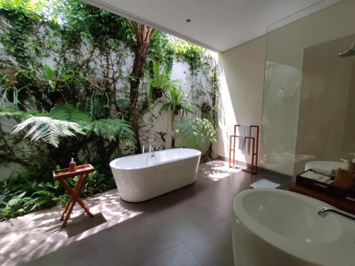 a bathroom with a tub and a sink and a tree at Santun Luxury Private Villas-CHSE CERTIFIED in Ubud