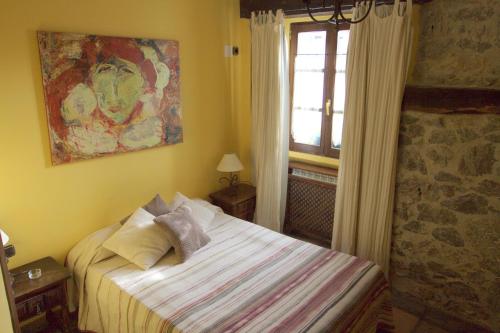 a small bedroom with a bed and a window at Hostal Rural Elosta in Lekunberri