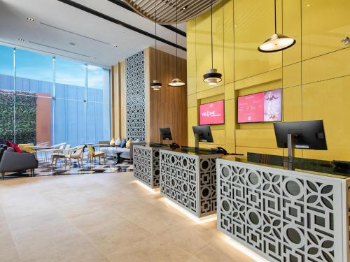a lobby with a waiting area with tables and chairs at ibis Bangkok Sukhumvit 24 in Bangkok