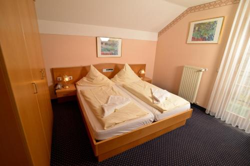 a bedroom with a bed with white sheets and pillows at Ferienhotel Rothbacher Hof in Bodenmais