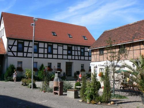 two buildings with red roofs and a courtyard with plants at Pension Schütze in Daasdorf am Berge