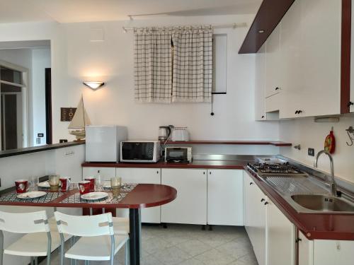 una cucina con armadi bianchi e tavolo in legno di Giulia & Giovanna Apartments a Levanto