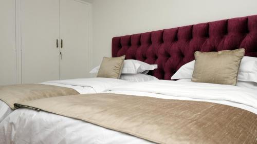 2 camas en un dormitorio con cabecero rojo en The Observatory, Luxury Suite in Observatory Home, en Johannesburgo