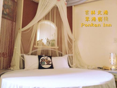 a bedroom with a white bed with a mirror at Ponkan Inn in Beigang