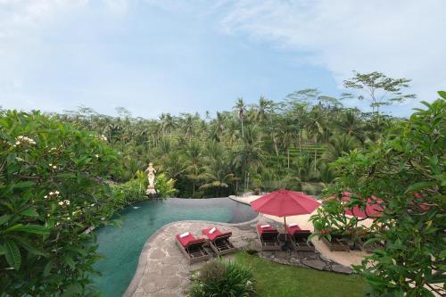 a pool at a resort with chairs and umbrellas at Puri Sebali Resort in Ubud