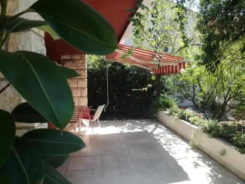 a patio with a red umbrella and a table and chairs at Apartment Petrović in Korčula