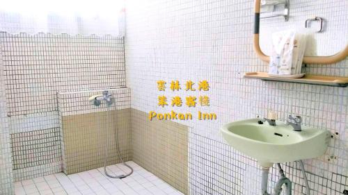 baño con lavabo y pared de azulejos blancos en Ponkan Inn, en Beigang