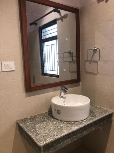 - Baño con lavabo, espejo y ventana en Jungle Safari Resort, en Sauraha