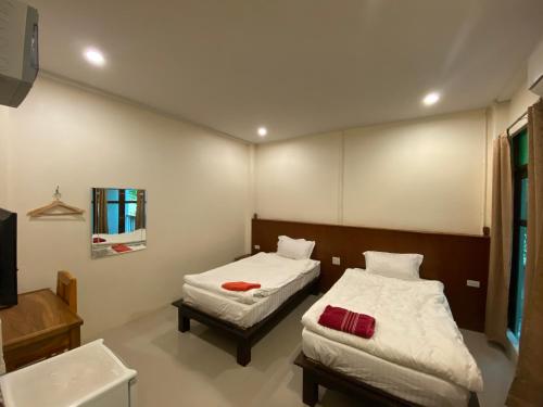 a bedroom with two beds and a sink and a mirror at Jitra Resort in Sukhothai