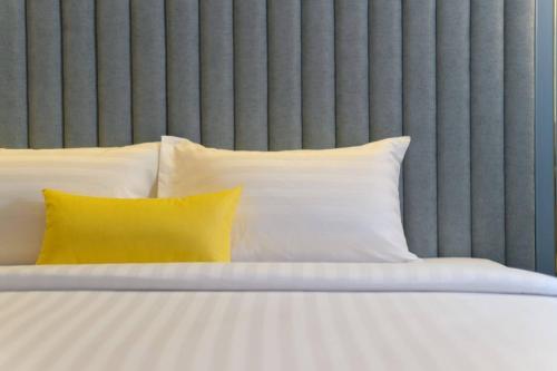 a bed with white pillows and a yellow pillow at The Mulberry Bangkok Khaosan Road in Bangkok