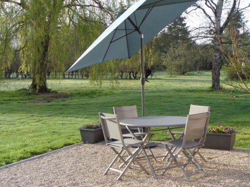 uma mesa e cadeiras com um guarda-sol num parque em la Monlassière em Vitry-aux-Loges