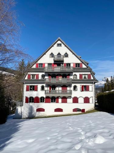 Un grand bâtiment blanc avec des fenêtres rouges dans la neige dans l'établissement Appartement Odyssée - Welkeys, à Megève