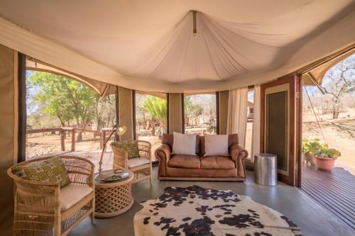 sala de estar con sofá y sillas en el porche en Karongwe Portfolio - Chisomo Safari Camp en Karongwe Game Reserve