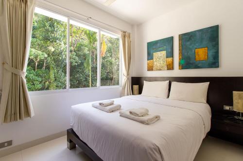 Kamala Hills Serviced Apartments في شاطئ كامالا: غرفة نوم بسرير كبير عليها منشفتين