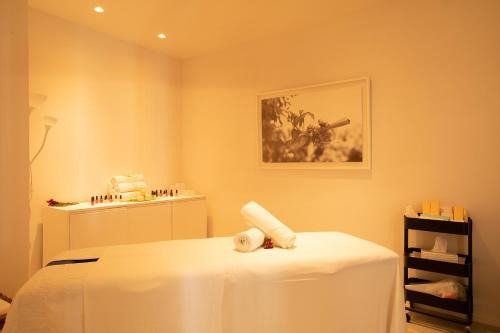 a white room with a bed and a shelf of cosmetics at Hotel Anfora Ibiza in Es Cana