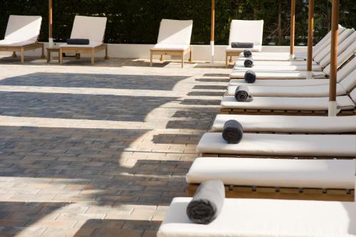 a row of white lounge chairs on a patio at Hotel Anfora Ibiza in Es Cana