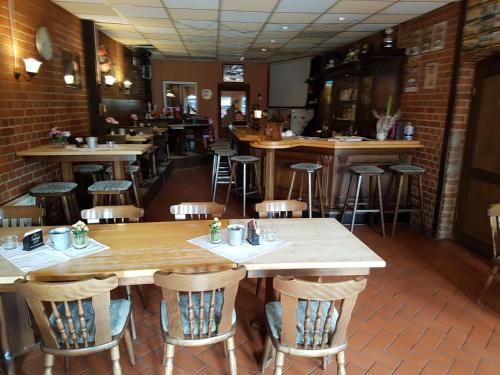 a restaurant with wooden tables and bar stools at Hotel Arkona in Genthin