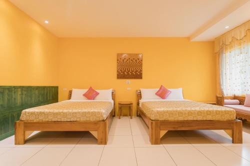 two beds in a room with yellow walls at Hai Yuan Bungalow II in Kenting