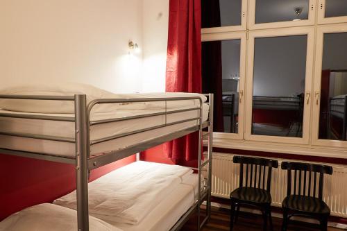 a bunk bed with two chairs in a room at Ballhaus Berlin Hostel in Berlin