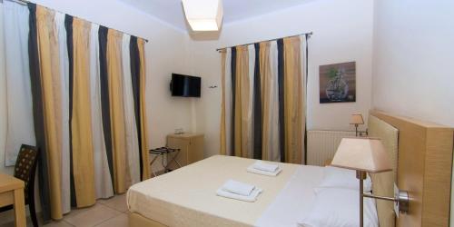 a room with a bed and curtains and a television at San Nectarios in Parga