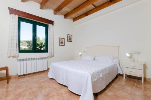 a white bedroom with a bed and a window at Pula Viñas in Son Servera