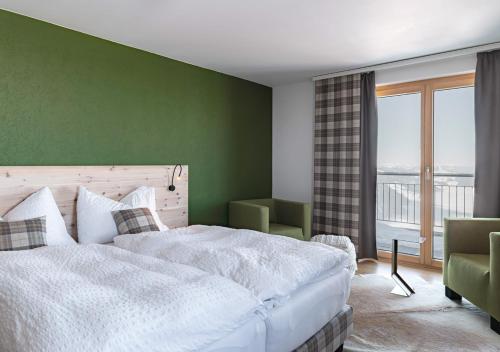 a bedroom with a white bed and a green wall at Gipfelrestaurant Fronalpstock in Stoos