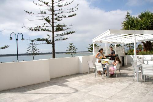 two people sitting at a table on a patio with a tree at Silvershore Apartments on the Broadwater in Gold Coast